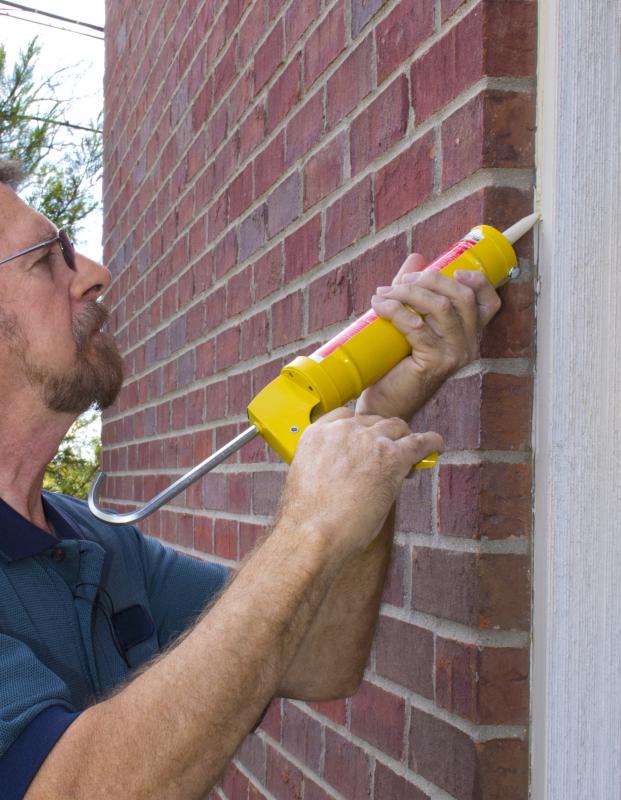 Applying rubber sealant to a wall.