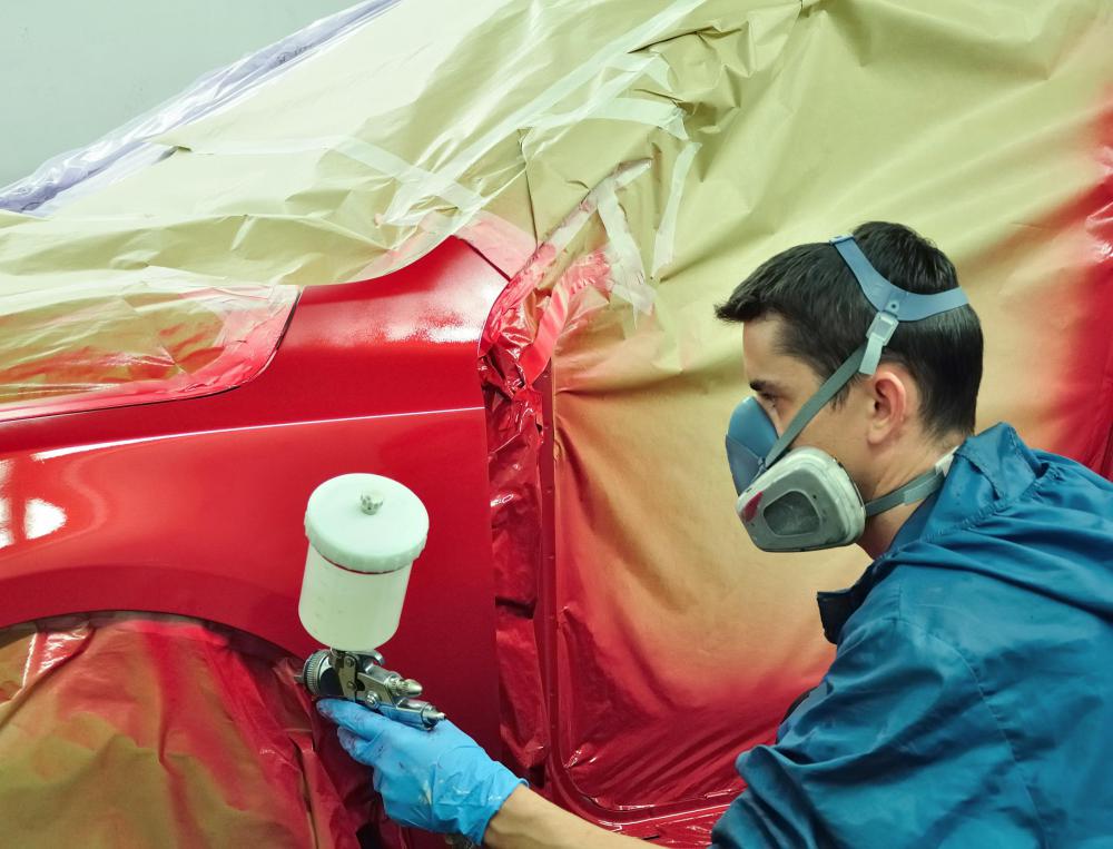 A man painting a car with flat paint.