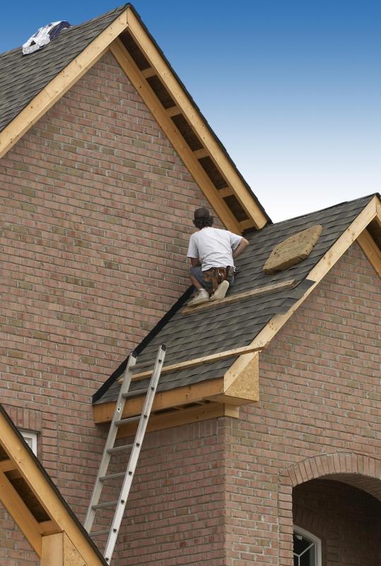 A roofer installing shingles on a house.