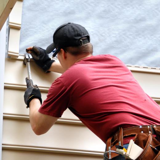 Slate roof tiles are arranged in rows over a few layers of tar paper and sealants.