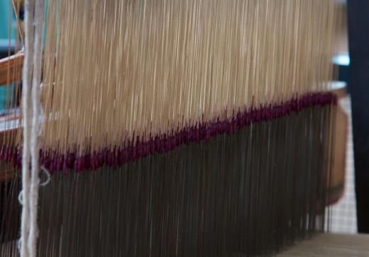 A jacquard loom utilizes an eye point needle to tightly weave threads when creating fabric.