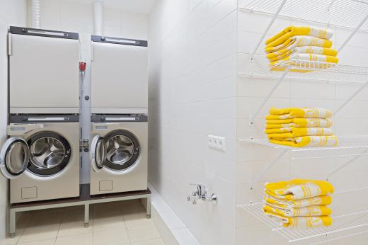 A pair of stacked washers and dryers in a locker room.