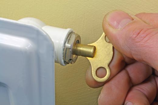 A person bleeding a hydronic radiator.